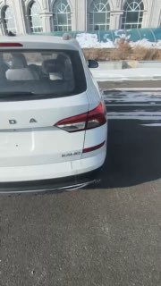 Кадр видео/превью: белая Skoda Kamiq едет по парковке/дороге, видно заднюю часть и общий облик автомобиля в движении.