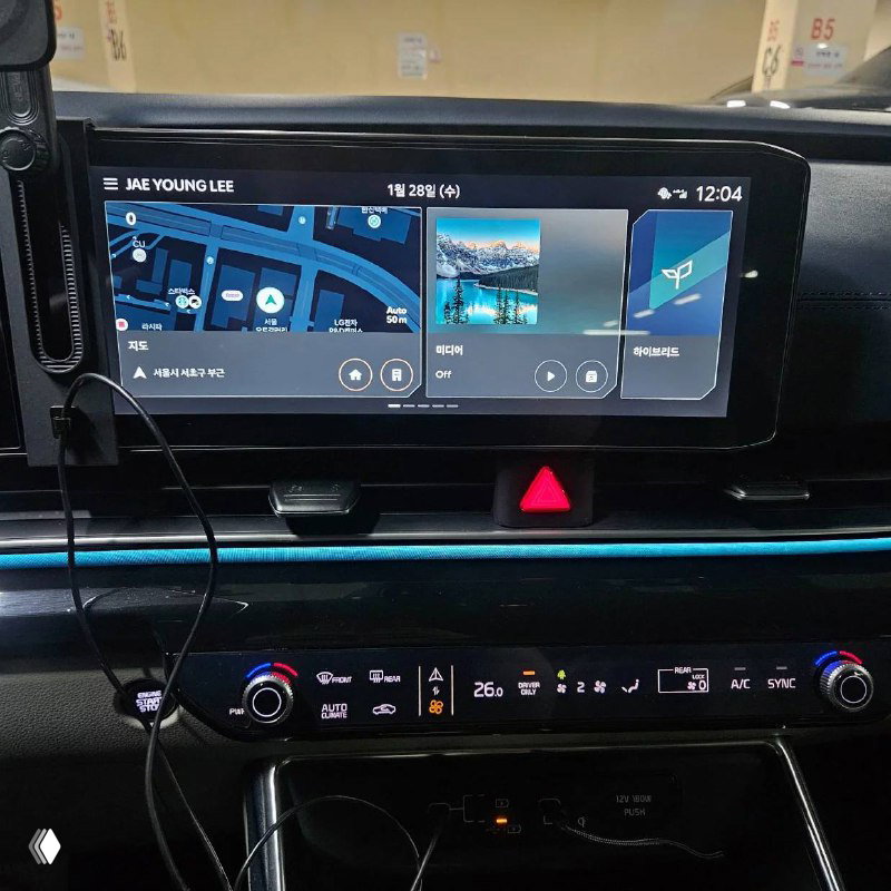 Крупный план мультимедийного дисплея KIA Carnival с навигацией, медиапанелью и управлением климатом, видны интерфейс и иконки.