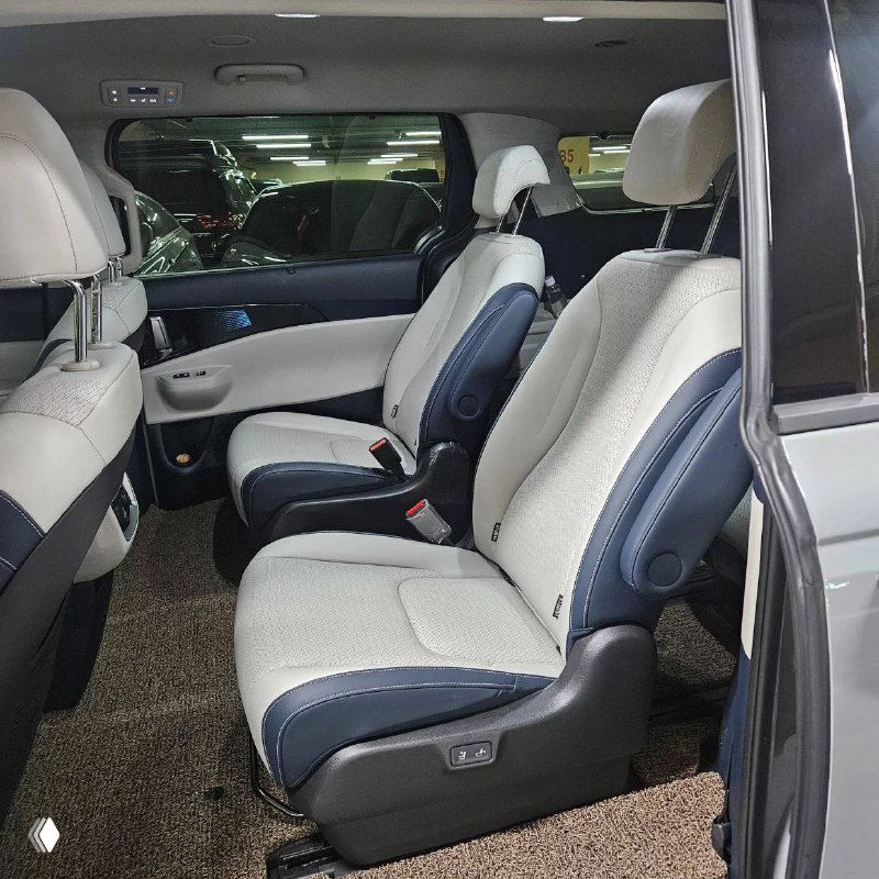 Второй ряд сидений KIA Carnival: два раздельных кресла в светлой тканевой обивке, удобные подлокотники и простор для ног.