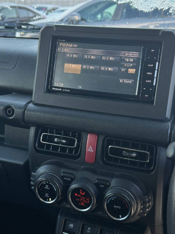 Мультимедийная панель и центр управления Suzuki Jimny: экран, кнопки и вентиляционные решётки, крупный план приборной панели и элементов управления мультимедиа в салоне.