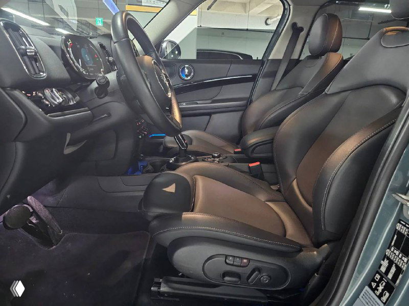 Передние кресла и водительское место Mini Cooper Countryman 2022 в кожаной отделке: видны регулировки сидений, подлокотник и общая эргономика салона.