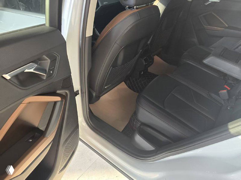 Задние сиденья и пространство для пассажиров Audi Q3, видны чёрные кожаные кресла, отделка дверных панелей и свободное место для ног на заднем ряду.