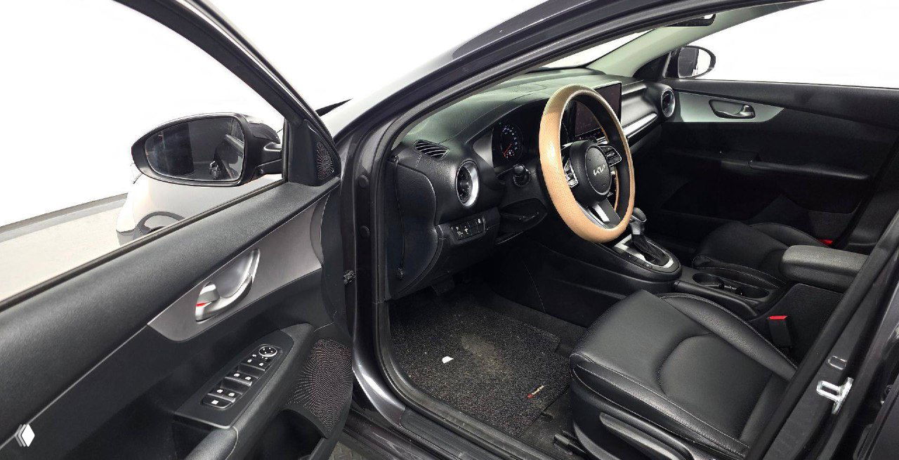 Открытая передняя дверь KIA K3 2021: вид на водительское место, дверную панель, электрические органы управления и состояние порога.