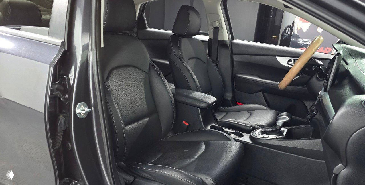 Передние сиденья KIA K3 2021 в салоне: чёрная обивка, подлокотник и пространство между сиденьями, видна общая аккуратность интерьера.