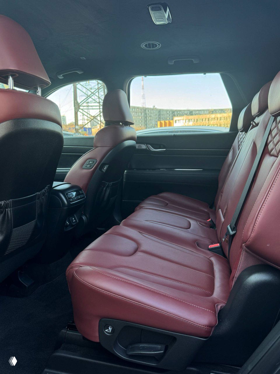 Задний ряд бордовых кожаных сидений Hyundai Palisade, простор для пассажиров и вид на заднюю вентиляционную зону и карманы спинок.