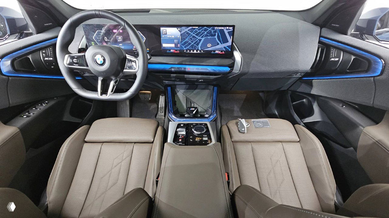 Салон BMW X3: обзор панели, мультимедиа-панели и рулевого колеса в интерьере с коричневой кожей и декоративными синими вставками.