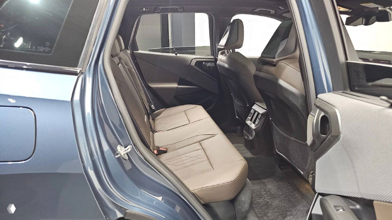 Вид на задний ряд сидений BMW X3: коричневая кожаная обивка, пространство для ног и центральная консоль с вентиляционными дефлекторами.