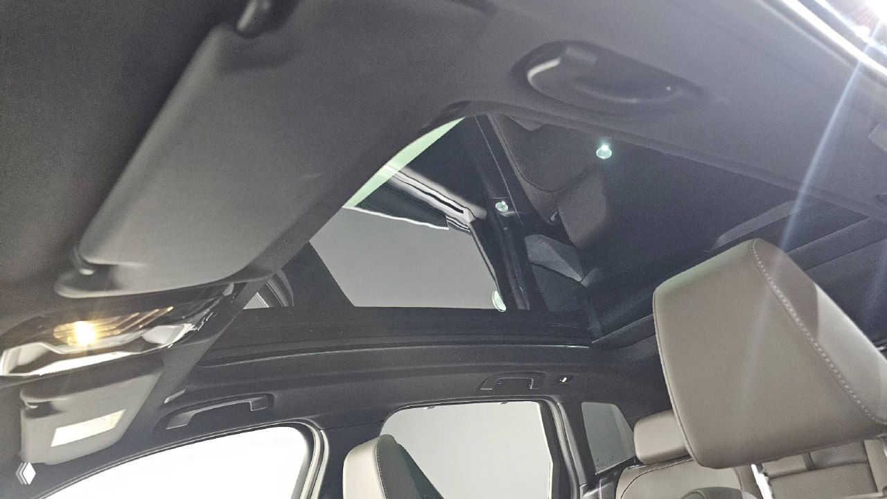 Панорамная крыша BMW X3: вид из салона вверх на стеклянный люк, подсветка и элементы обивки потолка автомобиля.