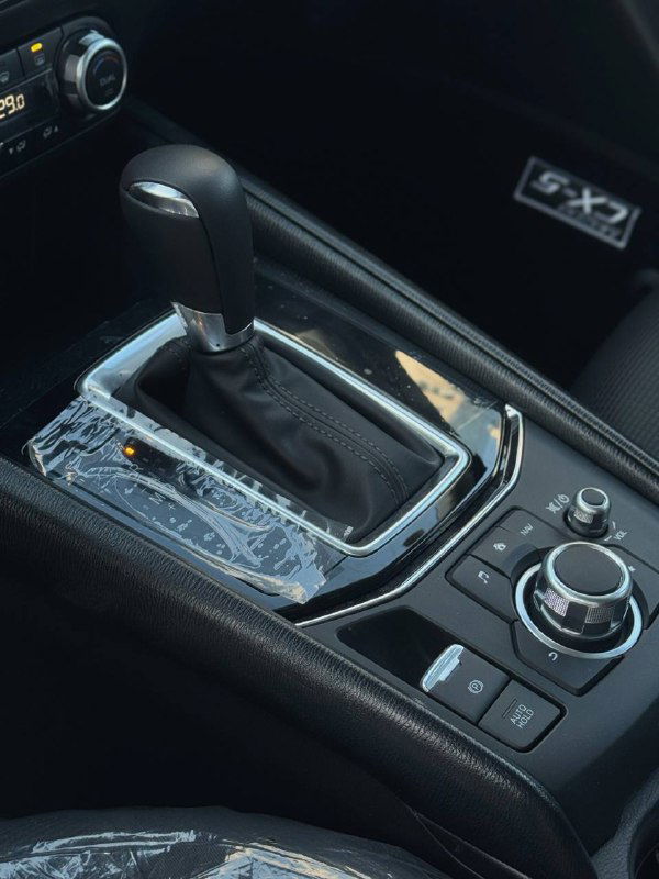Селектор АКПП и центральный контроллер мультимедиа в Mazda CX-5 2025, выглядит как стандартная комплектация с защитной пленкой на элементов.