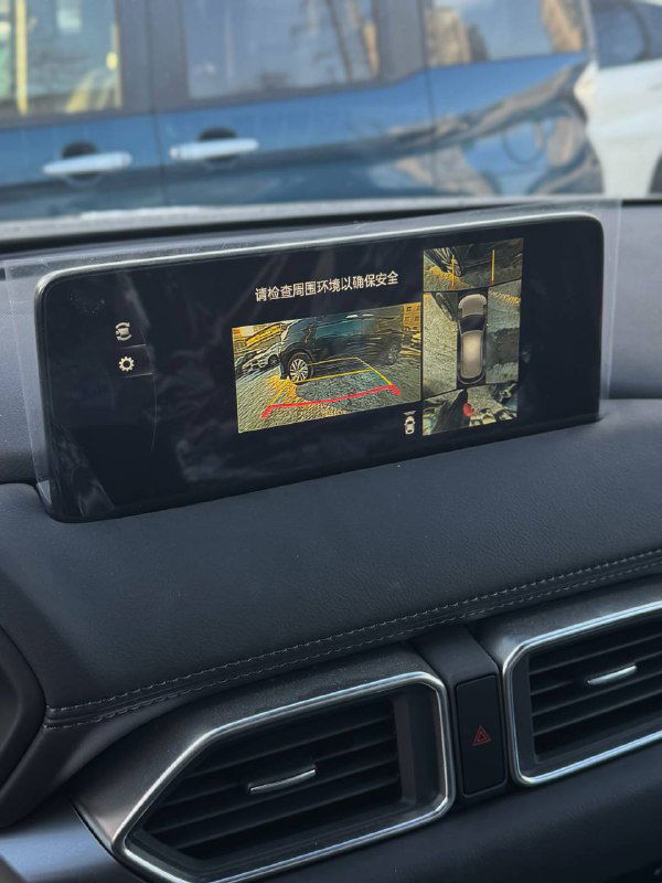 Экран мультимедиа показывает изображение с камеры заднего вида и обзор 360 градусов в Mazda CX-5 2025, демонстрация установленных камер.