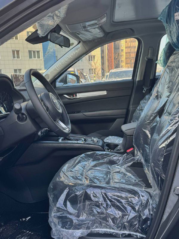 Передние сиденья Mazda CX-5 2025 с защитной упаковкой, видно оформление салона и перешив в кожу, сохранённая заводская упаковка.