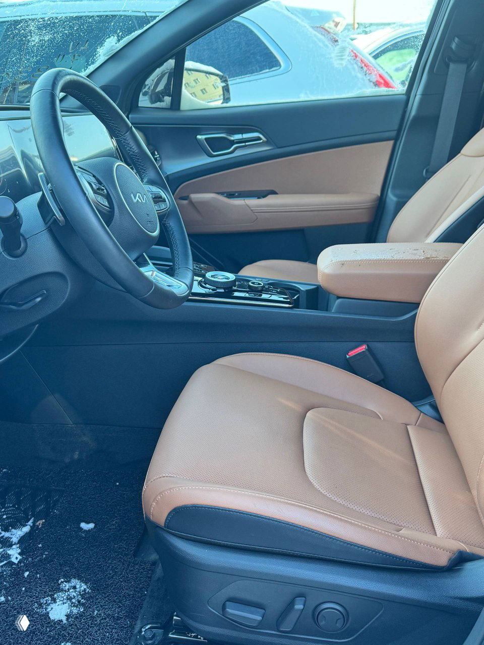 Вид на переднее пассажирское кресло с коричневой кожаной обивкой, центральный тоннель и органы управления между сиденьями