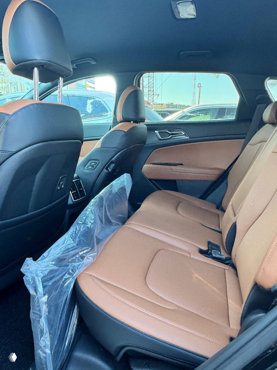 Задний ряд сидений KIA Sportage в коричневой обивке, видно пространство для пассажиров и пластиковую защитную плёнку на полу