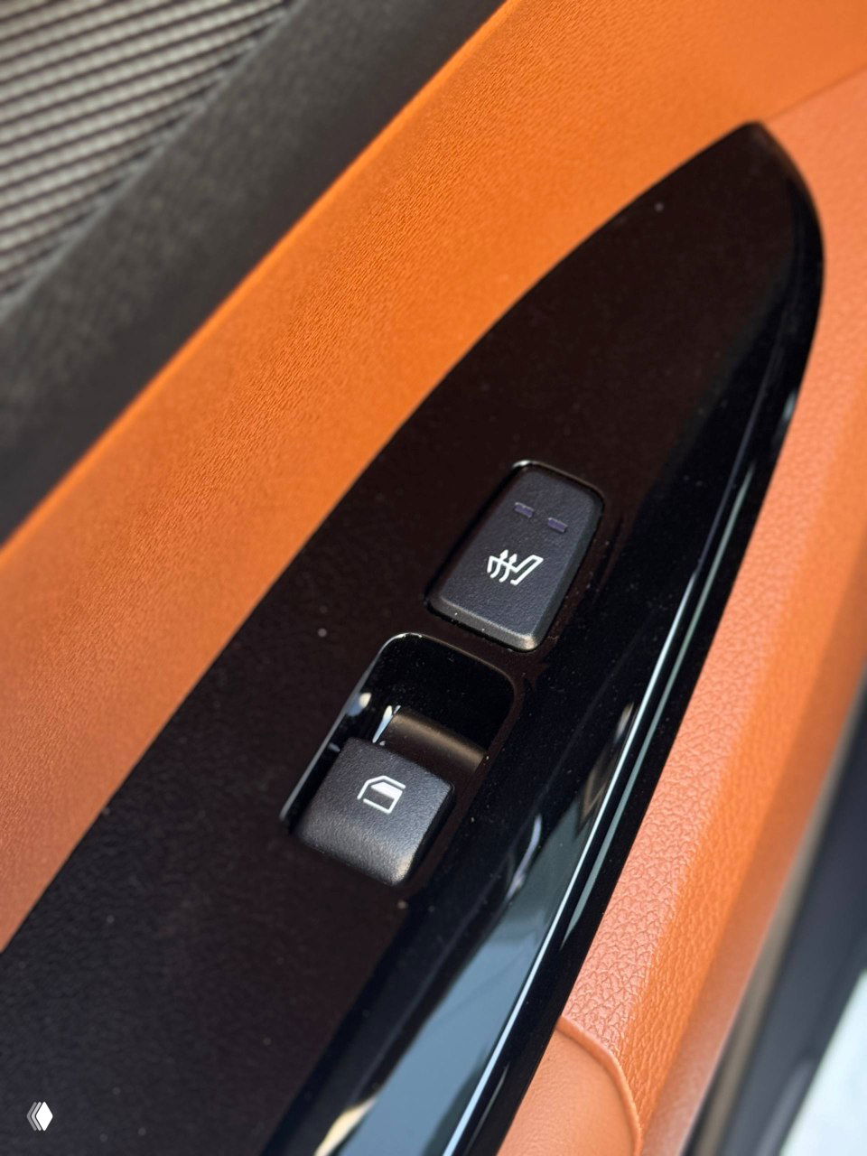 Крупный план блока кнопок на дверной панели с переключателем подогрева сиденья и кнопкой стеклоподъёмника на глянцевой накладке