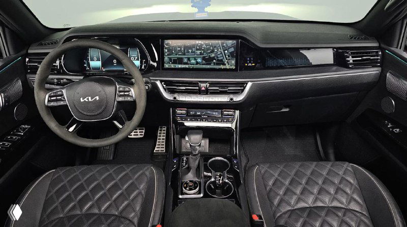Интерьер KIA Mohave: вид на переднюю панель, руль с логотипом Kia, мультимедийную панель и отделку салона с перфорированной кожей и строчкой.