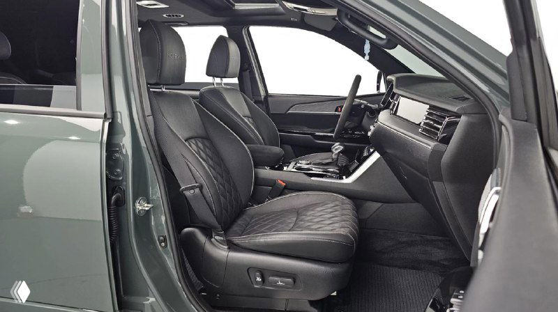 Фотография передних сидений KIA Mohave в кожаной отделке, видны регулировки, подлокотник и детали отделки дверей в благородном тёмном тоне.