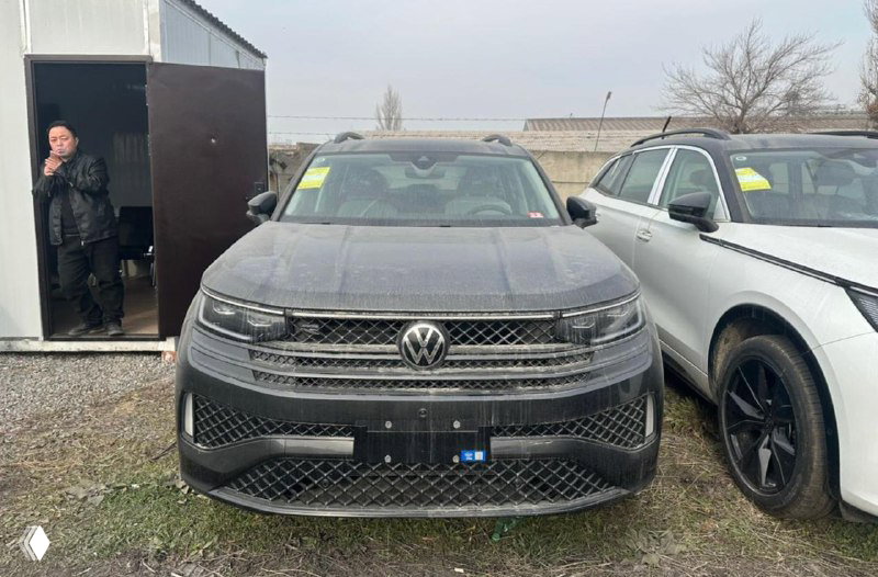 Фронтальный вид Volkswagen Tavendor на стоянке импорта в Киргизии — автомобиль на фоне контейнера и других авто, видна лицевая часть и решётка радиатора