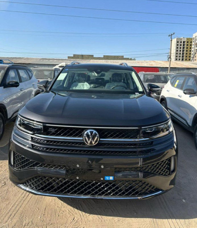 Ещё один вид спереди Volkswagen Tavendor — тёмный кузов, парковка автомобилей под открытым небом, видна лицевоя панель и фары