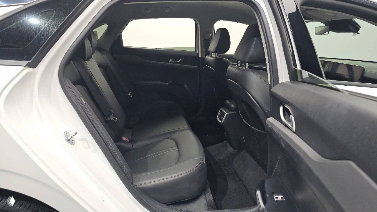 Задний ряд сидений KIA K5 2024: чёрная обивка, три посадочных места, пространство для ног и вид на заднюю панель салона в студийной фотографии.