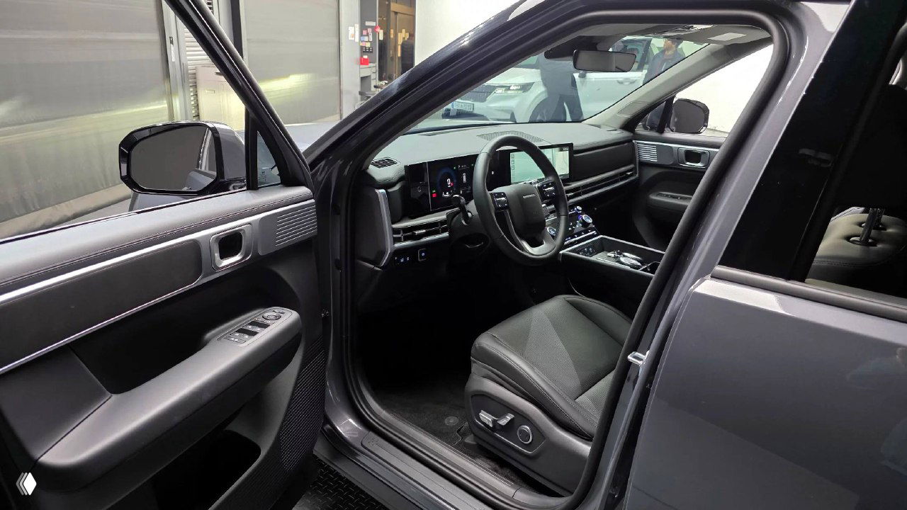 Открытая водительская дверь Hyundai Santa Fe 2025 — вид в салон, водительское кресло, рулевое колесо и элементы управления на дверной панели.