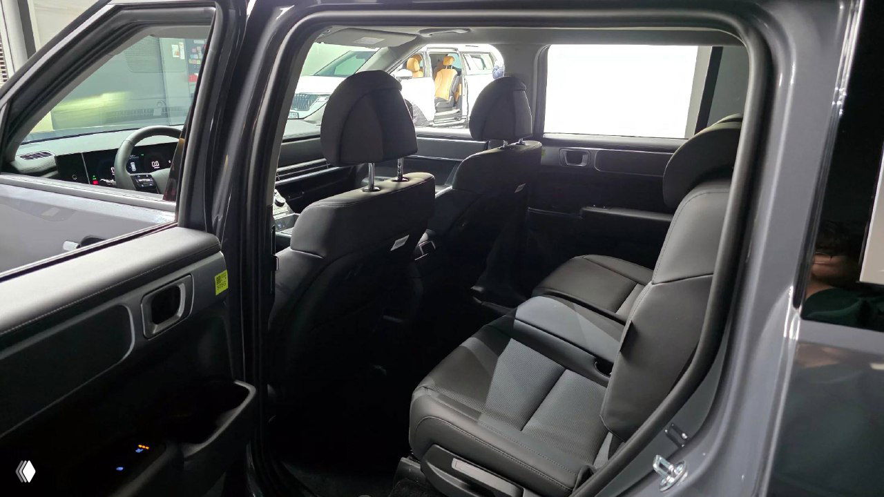 Второй ряд сидений Hyundai Santa Fe 2025, вид через открытую заднюю дверь — подлокотник, пространство для ног и состояние обивки кресел.