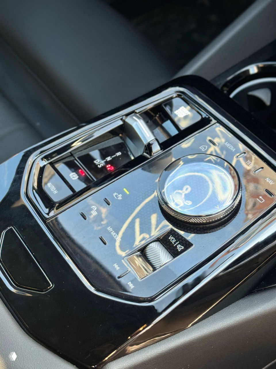 Крупный план центрального джойстика управления, селектора коробки передач и регулятора мультимедиа в салоне BMW 520i с блестящей отделкой.