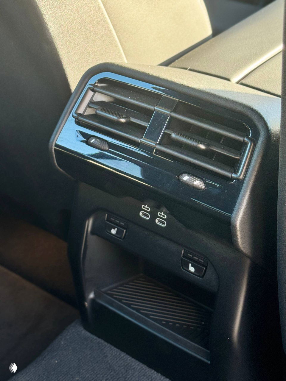 Крупный план заднего воздуховода и панели с USB/розетками, вид на элементы обогрева сидений и пространство для хранения в задней части салона.