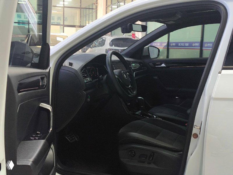 Вид открытой дверной проёма и водительского кресла Volkswagen T‑Roc с электроприводом; демонстрация состояния сидений и элементов управления