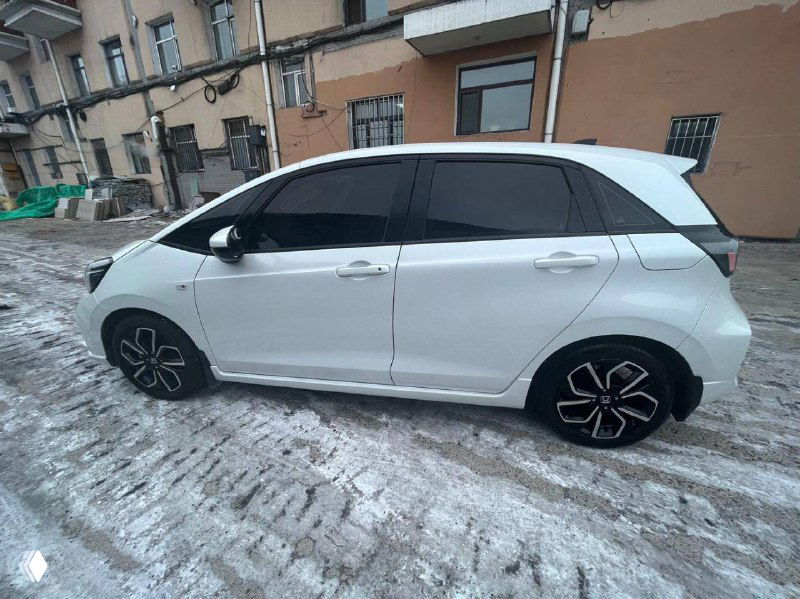 Боковой вид белого Honda Life 2022 с чёрными дисками на зимнем фоне, показывает двери, колёса и общий силуэт автомобиля.