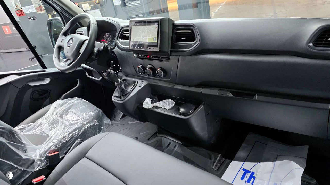 Салон Renault MASTER: общий вид кабины, пластиковая отделка, защищённые сиденья и центральная консоль с монитором и рычагом КПП.