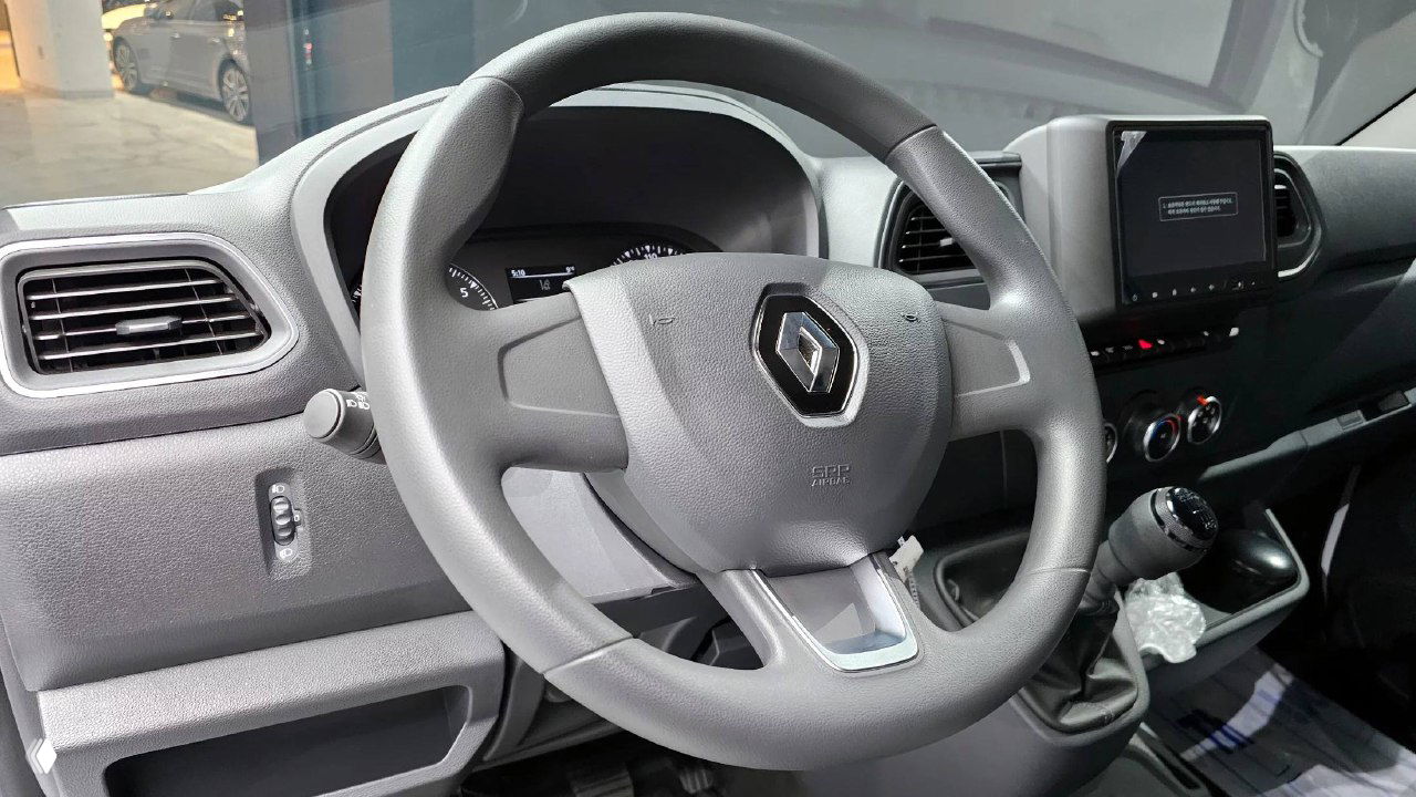 Рулевое колесо Renault с эмблемой марки, панель приборов и коробка передач — вид на водительское место и органы управления.