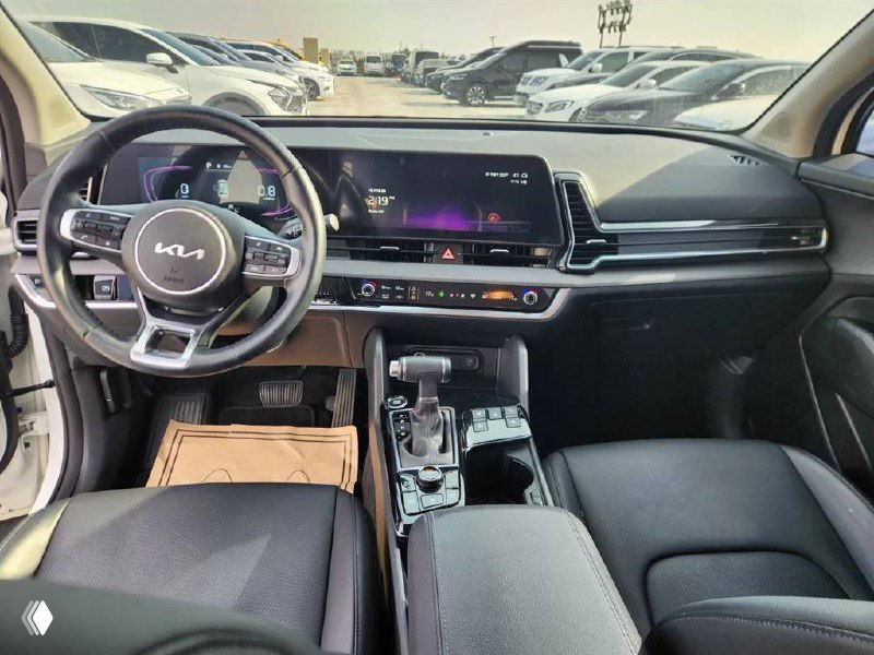 Салон KIA Sportage 2024 — панорамная фотография приборной панели и центрального дисплея, вид рулевого колеса и передней панели с мультимедиа.