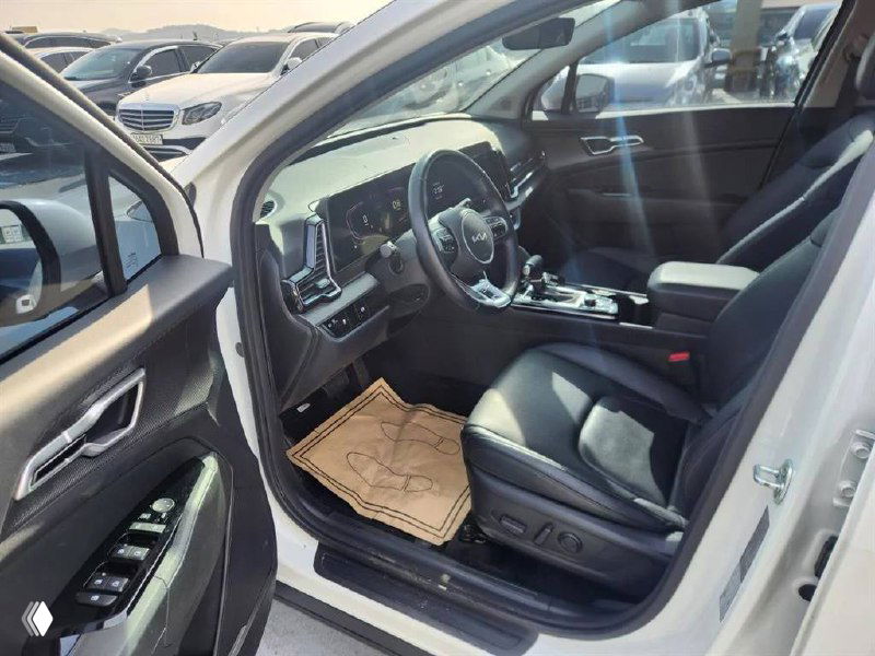 Водительская дверь и переднее сиденье KIA Sportage 2024 — вид открытого салона, электрорегулировки сиденья и элементы внутренней отделки.