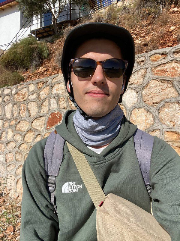 Селфи автора в толстовке, с бафом на шее и солнцезащитными очками, шлем виден рядом — пауза в поездке на скутере по Турции.