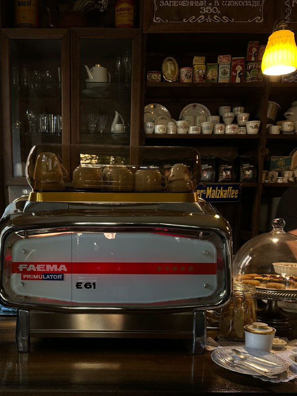 Интерьер кафе в Калининграде с профессиональной эспрессо-машиной, витриной кондитерских изделий и уютной атмосферой, подходящей для завтрака туристов.