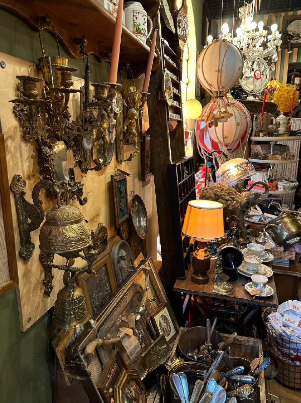 Интерьер антикварной лавки в Калининграде: стеллажи и столы с винтажными предметами, зеркалами, подсвечниками и декоративными элементами для туристов и коллекционеров.