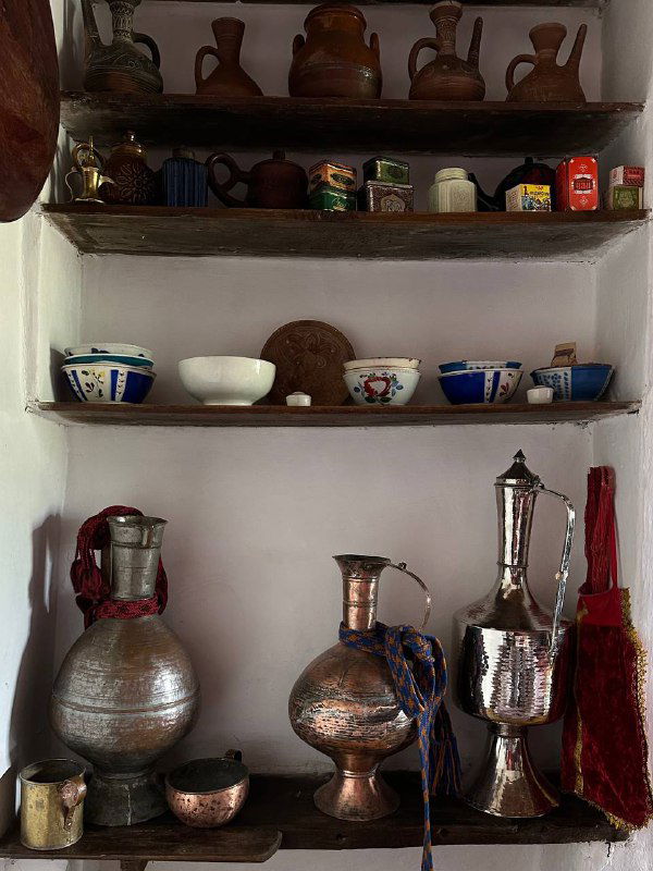 Полки в сакле с традиционной посудой и медной утварью, декоративные миски и бутылочки в аутентичном интерьере дома‑музея.