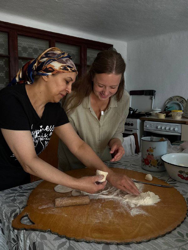 Две женщины готовят тесто на большом столе, традиционная деревенская кухня и процесс лепки аварского чуду в домашних условиях.