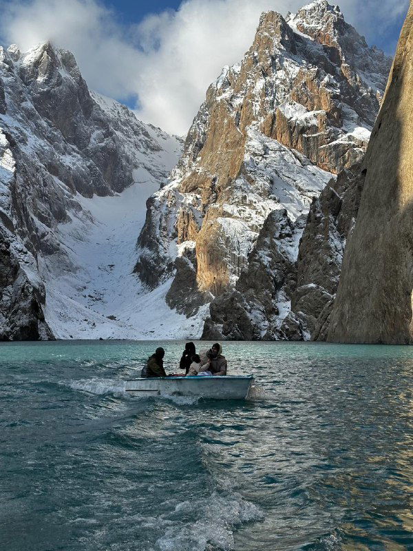 Небольшая лодка на бирюзовом озере в окружении заснеженных пиков Тянь-Шаня — ледниковая вода, ощущение изолированности и первооткрытия.