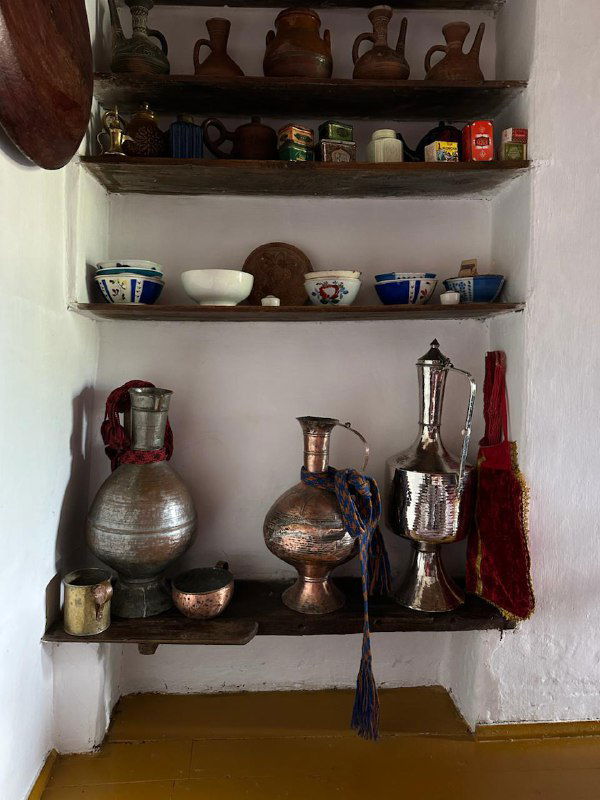 Полка с металлической утварью и аксессуарами традиционного быта — элементы интерьера, показывающие историческую кухню региона.