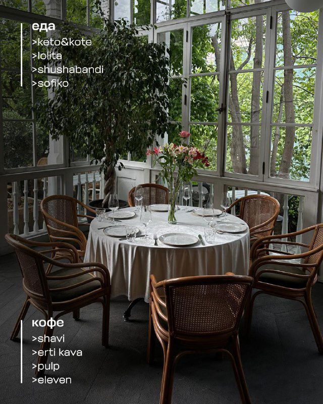 Ресторанный зал с белыми скатертями и видом на сад: стол для уютного завтрака или ужина в одном из камерных тбилисских заведений.