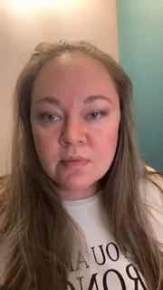 Крупный план женщины в помещении, нейтральное выражение лица, светлая футболка с принтом, размытый бирюзовый фон — превью к эфиру.