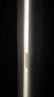 Узкая вертикальная полоса света между тёмными поверхностями — абстрактная фотография света и тени, передающая атмосферу расслабления и уединения.