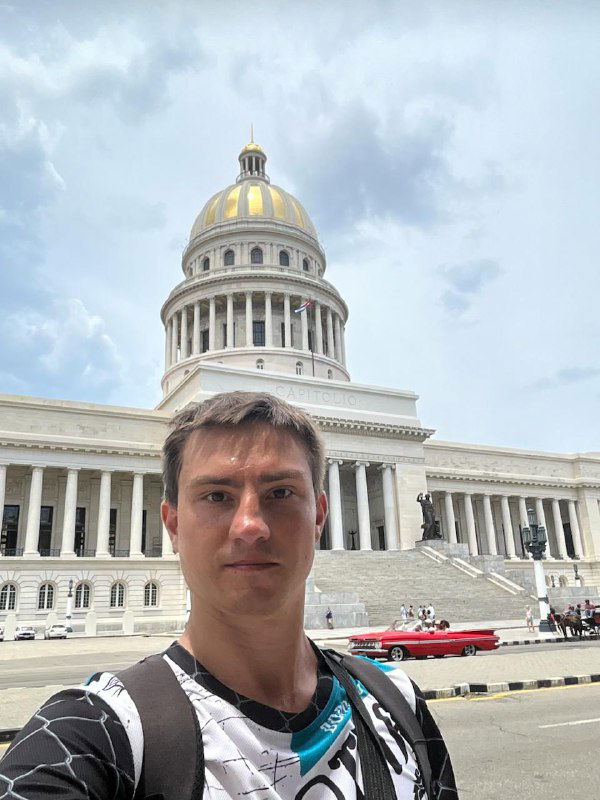 Селфи автора с Капитолием на заднем плане — лицо в центре кадра, купол и колонны исторического здания позади.