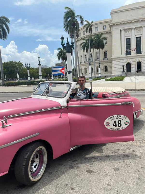 Автор за рулём розового кабриолета с наклейкой номера 48 на фоне Капитолия — яркая туристическая фотография с улыбкой.