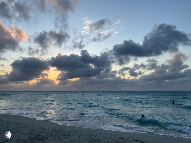 Закат над морем на пляже Варадеро: спокойная вода, пляж и драматичное небо с облаками во время захода солнца.
