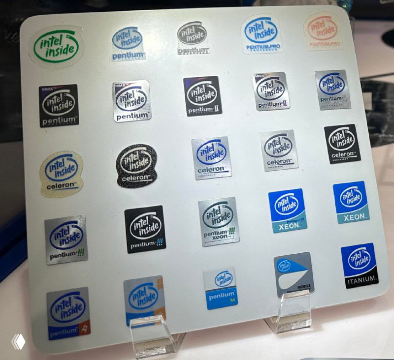 Фотография коллекции наклеек «Intel Inside» и логотипов разных эпох: Pentium, Celeron, Xeon и другие бренды Intel на демонстрационной панели.