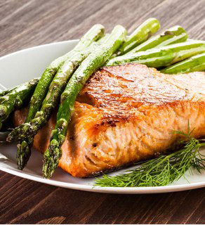 Кусок лосося, поджаренный на гриле, с зелёной спаржей и укропом на тарелке — акцент на текстуре и лёгком дымном аромате блюда.