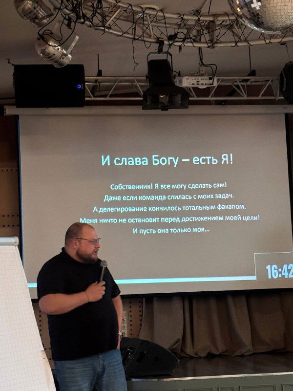 Докладчик на сцене HR‑конференции: выступление с проектором и слайдом, кадр с публичной лекцией в клубе «Эволюция».