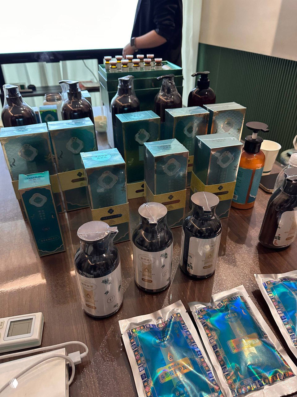 Стол с пробниками косметики и упаковками китайской продукции для ухода за волосами и массажа — ассортимент для демонстрации партнёрам и клиентам.